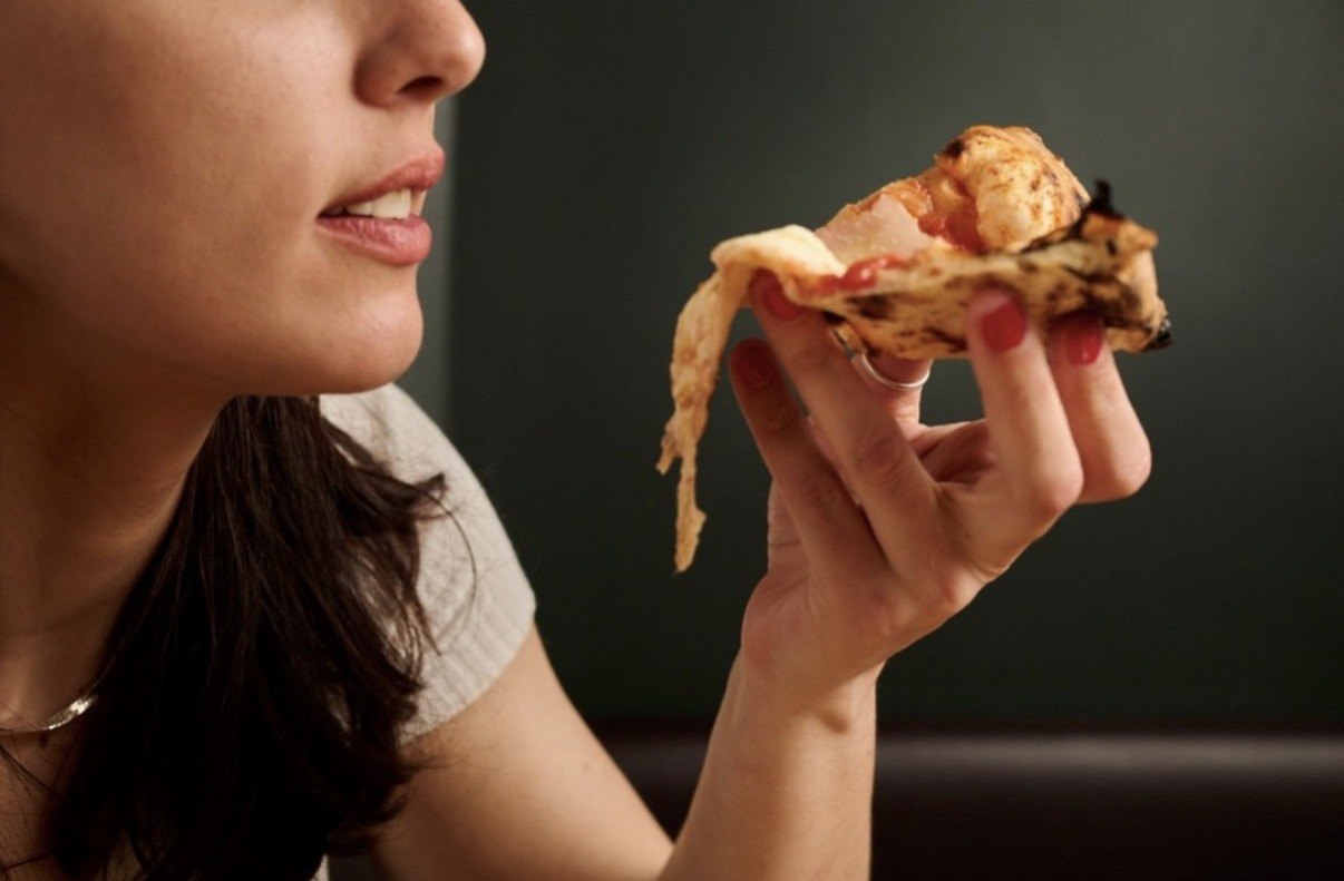 Ospite PizzaRé che assapora una fetta di pizza napoletana filante