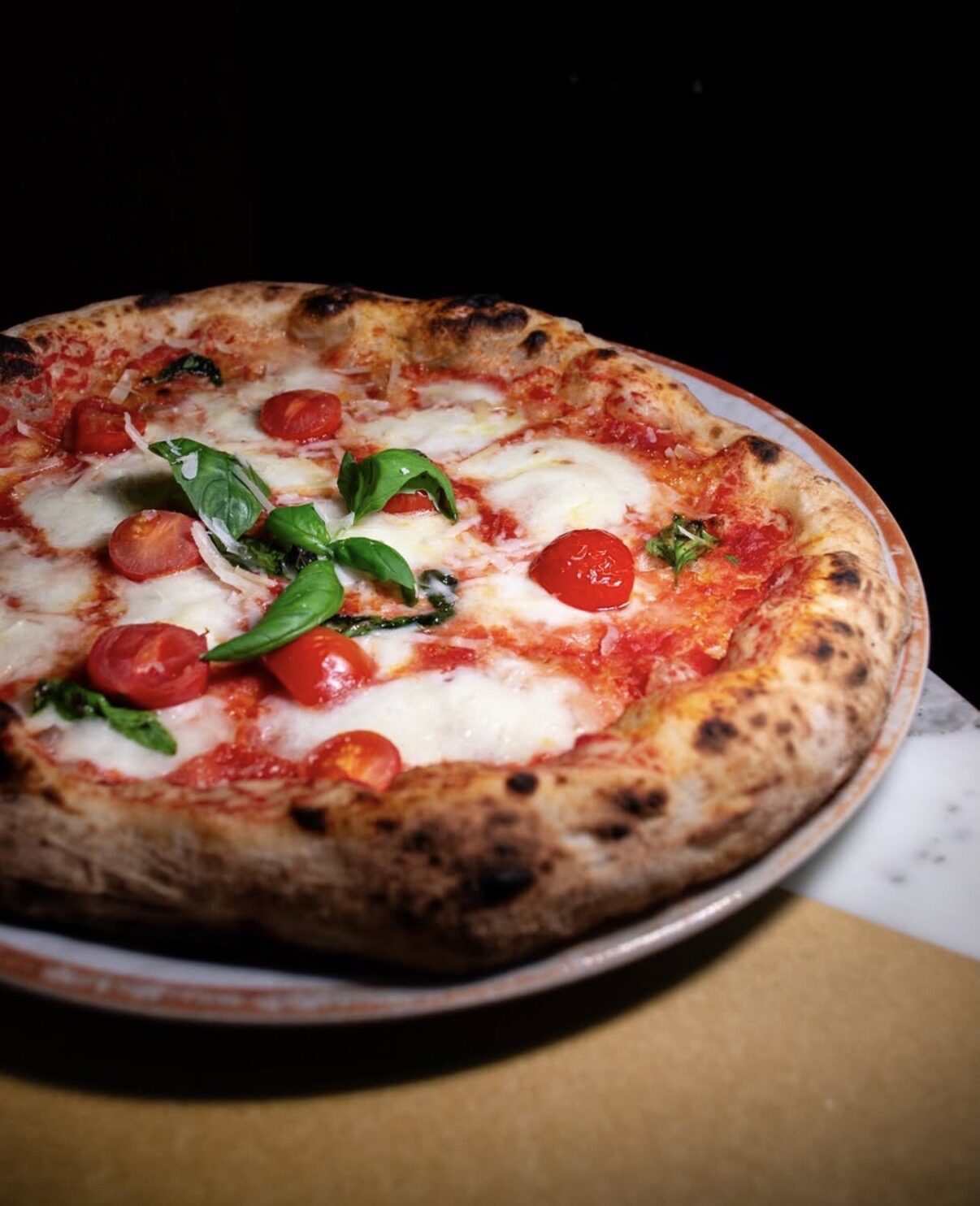 Margherita con pomodorini e basilico su piatto bianco