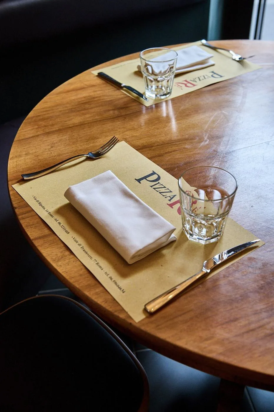 Tavolo rotondo in legno apparecchiato con la tovaglietta PizzaRé